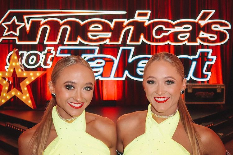 The Rybka Twins pose in front of the America's Got Talent key art